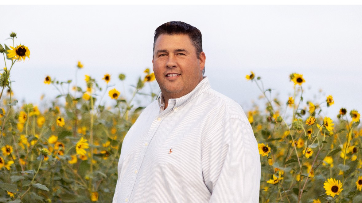Travis LaQua, owner and builder at LK Contracting, standing in a field of sunflowers