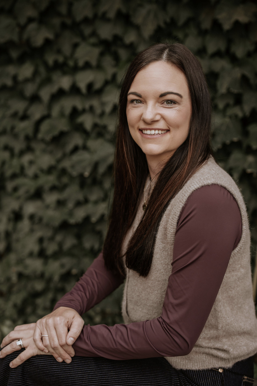Mallory Kuiper, owner and realtor at LK Contracting, smiling in front of ivy